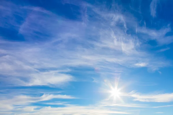 Sonniger Hintergrund blauen Himmels mit echter Sonne und leichten Wolken — Stockfoto