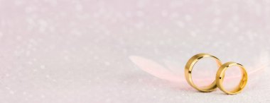 İki Altın Nikah Yüzüğü ve Hafif Melek Tüyü. Evlilik için yumuşak bir arka plan, uzun bir arkaplan.