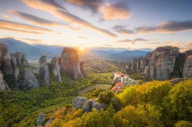 Yunanistan, Meteora 'nın panoramik manzarası. Gerçek güneş ve günbatımı gökyüzü ile romantik bir günbatımı zamanı. Meteora - inanılmaz kum taşı oluşumları. Meteora bölgesi UNESCO Dünya Mirası 'nda yer almaktadır.