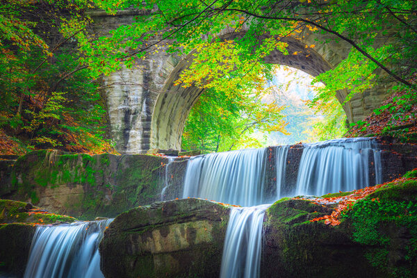 Beautiful  landscape - river waterfall in colorful mountain forest park  with old bridge