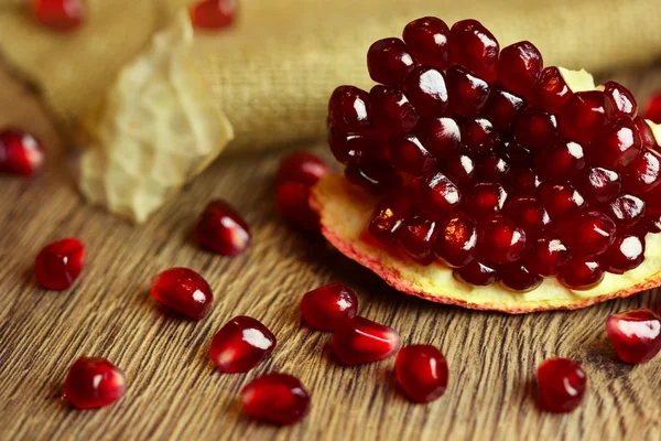 Raw pomegranate with seeds on wood — Stock Photo, Image