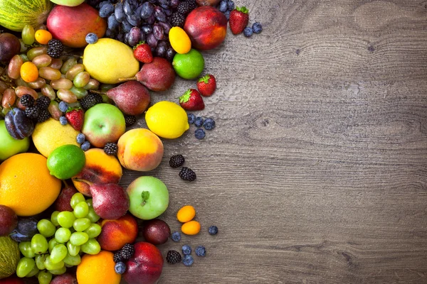 Olika ekologiska frukter med vatten droppar på träbord tillbaka — Stockfoto