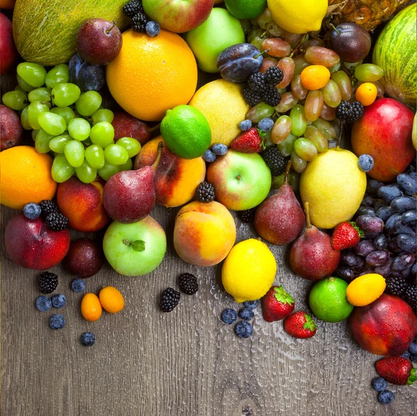 Ekologiska frukter med vatten droppar på mörka träbord — Stockfoto