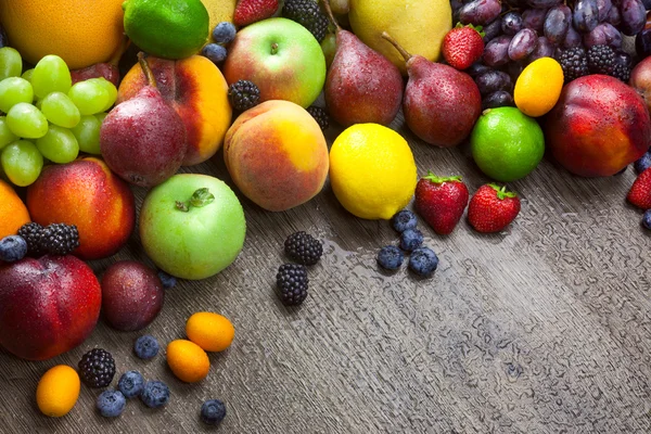 Gemischte frische Früchte auf dem hölzernen Hintergrund mit Wassertropfen — Stockfoto