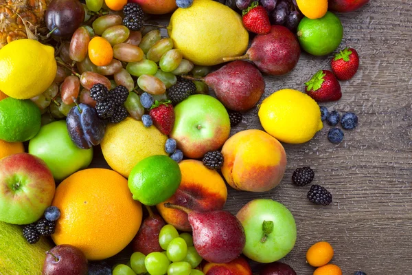 Mix van kleurrijke vruchten met water druppels op houten achtergrond — Stockfoto