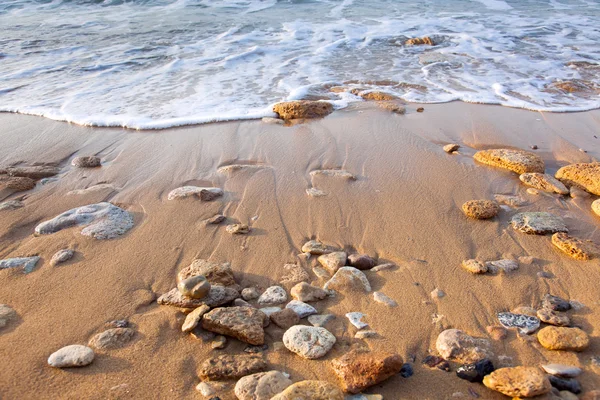 Onda do mar na praia com areia e pedras — Fotografia de Stock