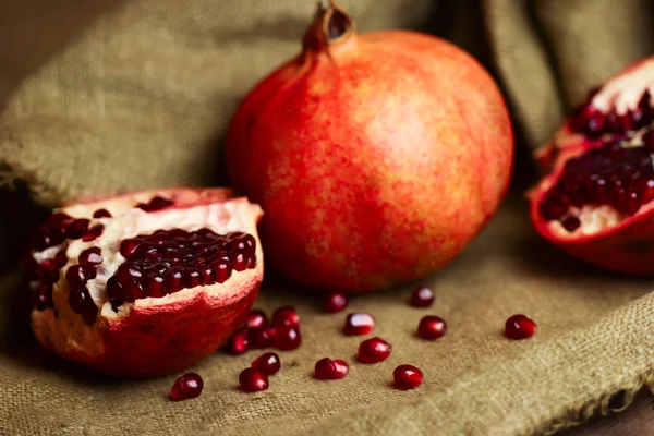 Raw red pomegranate with seeds on sacking — Stock Photo, Image