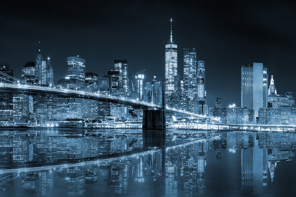 New York - Manhattan Skyline with skyscrapers and famous Brooklin Bridge by night with reflection, black and white blue toned