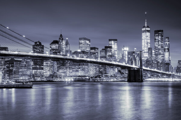 View of Manhattan with skyscrapers and old Brooklin Bridge by night, New York City illumination