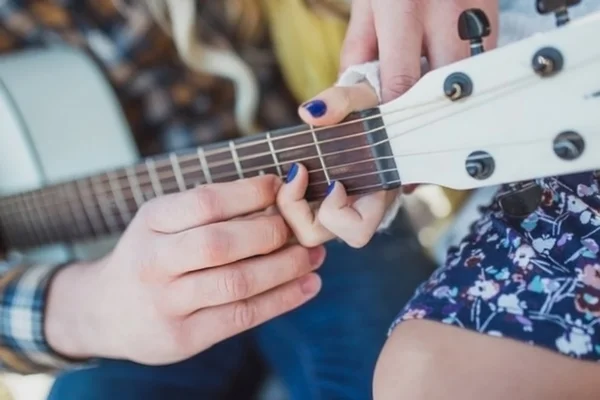 Pareja sostener y tocar la guitarra acústica, de cerca Imágenes de stock libres de derechos