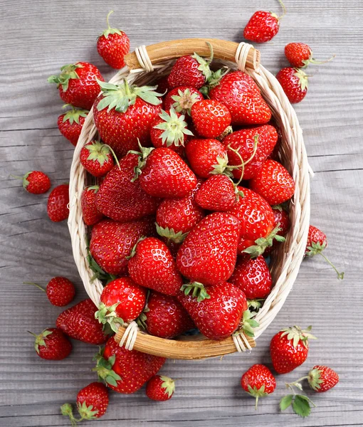 Sweet strawberries in basket on wooden table.