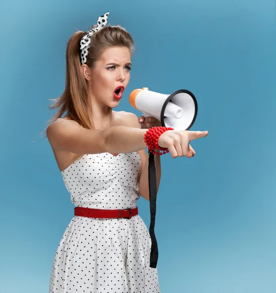 Formidable pin-up girl shouting into a megaphone, mouthpiece, speaking trumpet. Filmmaking or film production concept