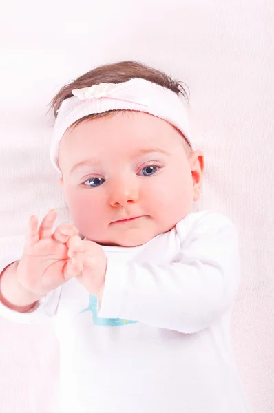 Lustiges Baby-Mädchen auf rosa Decke. — Stockfoto