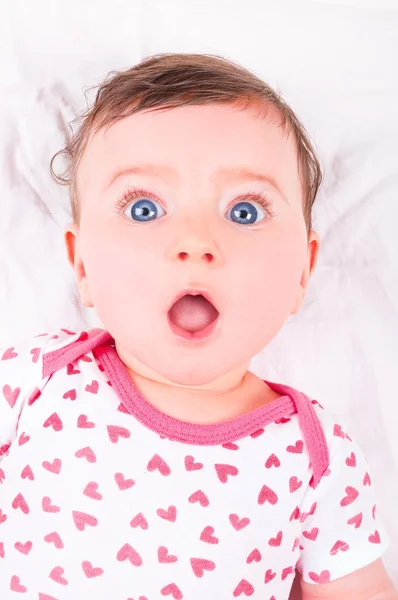 Meisje van de baby met grappige uitdrukking op witte deken. — Stockfoto