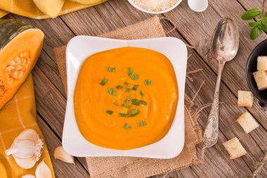 Beyaz tabakta patatesli balkabağı kremalı çorba.