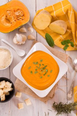 Beyaz tabakta patatesli balkabağı kremalı çorba.