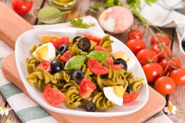 Fusilli pasta with cherry tomatoes, eggs and black olives.