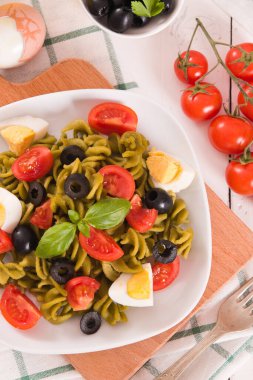 Fusilli pasta with cherry tomatoes, eggs and black olives.