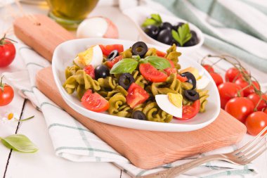 Fusilli pasta with cherry tomatoes, eggs and black olives.