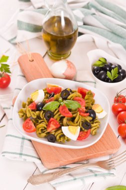 Fusilli pasta with cherry tomatoes, eggs and black olives.