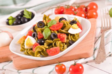 Fusilli pasta with cherry tomatoes, eggs and black olives.