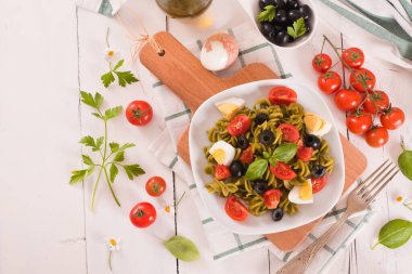 Fusilli pasta with cherry tomatoes, eggs and black olives.