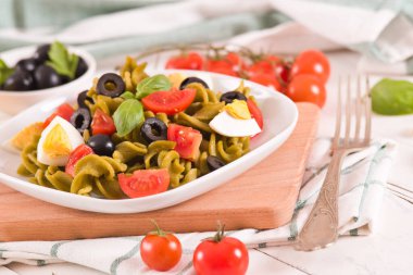 Fusilli pasta with cherry tomatoes, eggs and black olives.