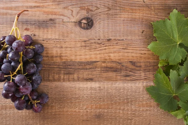 Afbeelding van een tros druiven op houten tafel — Stockfoto