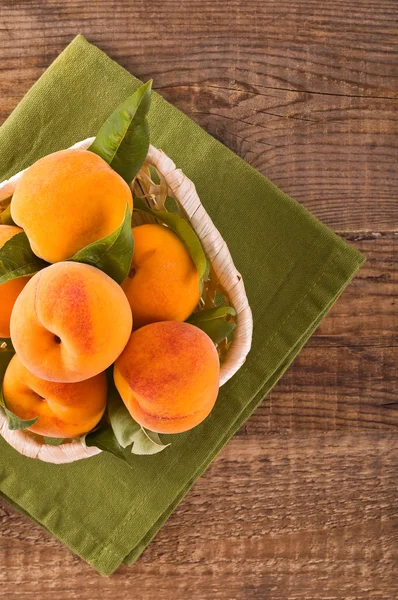 Oranje perziken in de mand. — Stockfoto