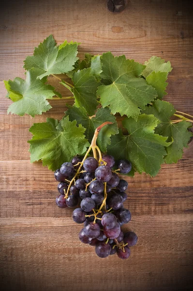 Imagen de un racimo de uvas sobre una mesa de madera . — Foto de Stock