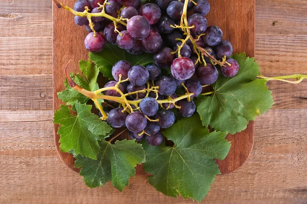 Ramo de uvas sobre mesa de madera . — Foto de Stock