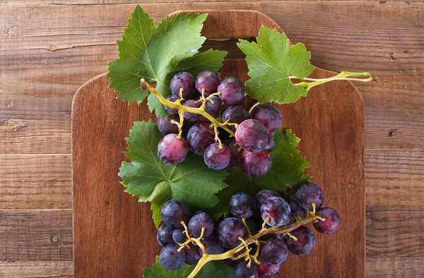 Ramo de uvas sobre mesa de madera . — Foto de Stock