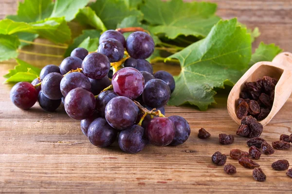 Druiven met rozijnen op houten tafel. — Stockfoto