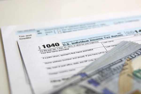 Formulaire d'impôt américain 1040 avec billets de 100 dollars américains . — Photo
