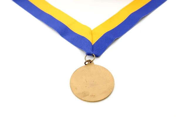 Золотая медаль на переднем плане на желтой голубой ленте — стоковое фото