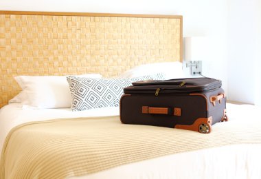 bavul içinde bir otel odasında yatağın üstüne