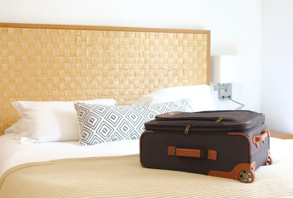 Beyaz otel yatağı üzerinde seyahat çantası 