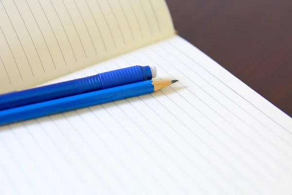 Drawing pencil and eraser over a white notebook — Stock Photo, Image