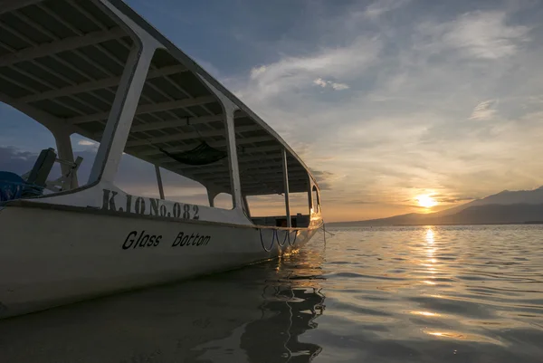 Matahari terbenam dengan perahu wisata dan masih air di Gili Air Island, Ind — Stok Foto