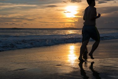 Kumsalda gün batımında Chenggu kumsalda, B koşan adam silüeti