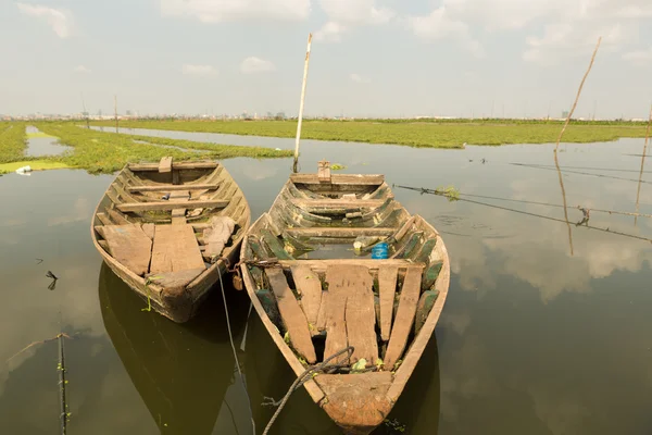 Barcos flutuando perto de campos de arroz com Phnom Penh no backgroun — Fotografia de Stock