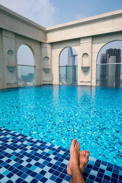 Feet over the sparkling pool on top of building with Saigon aeri