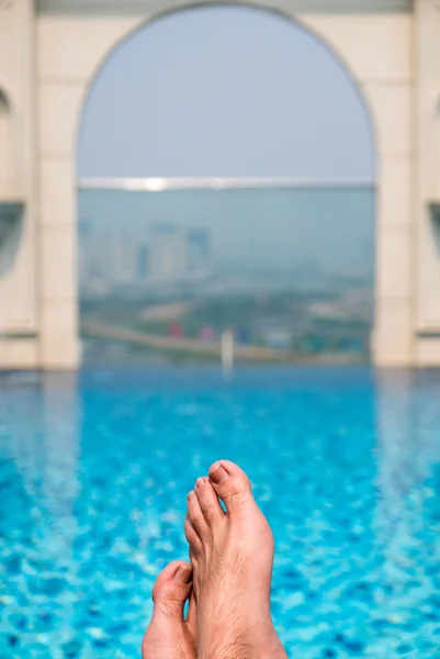 Feet over the sparkling pool on top of building with Saigon aeri — Stock Photo, Image