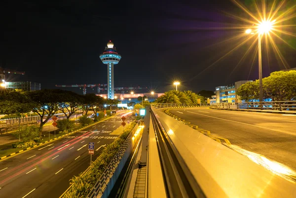 สนามบินชางงีของสิงคโปร์ในเวลากลางคืนพร้อมหอควบคุมการจราจรทางอากาศ — ภาพถ่ายสต็อก