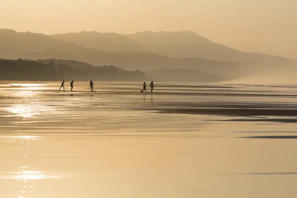 Silhouettes of people walking on the beach — Stock Photo, Image
