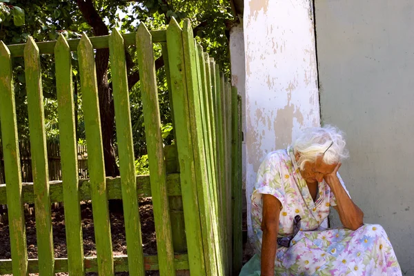 Vieja mujer solitaria sentada en la calle en Ucrania — Foto de Stock