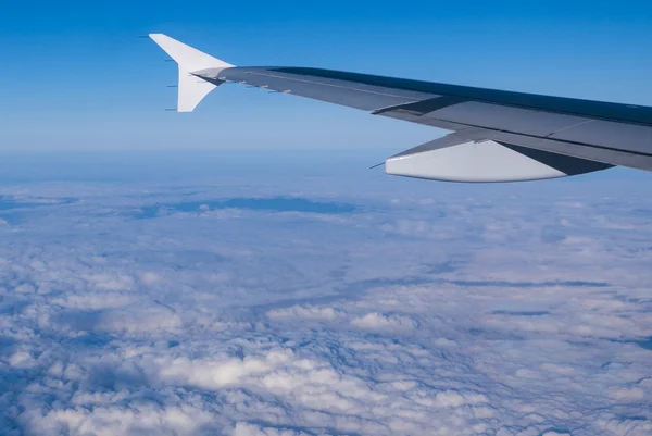Vinge på ett flygplan som flyger ovanför molnen — Stockfoto
