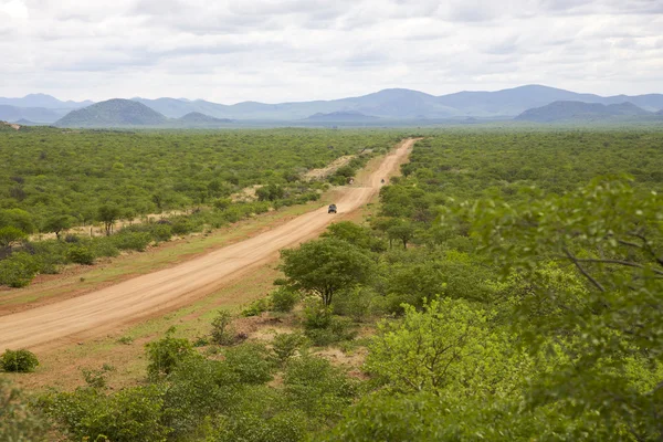 Camino de grava con 4x4 conducción de coches y las montañas de Zebra, Namibi —  Fotos de Stock