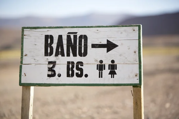 Wooden sign to the toilet in the Altiplano. Bolivia — Stockfoto