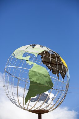 Iron earth globe structure with blue sky and South American cont clipart